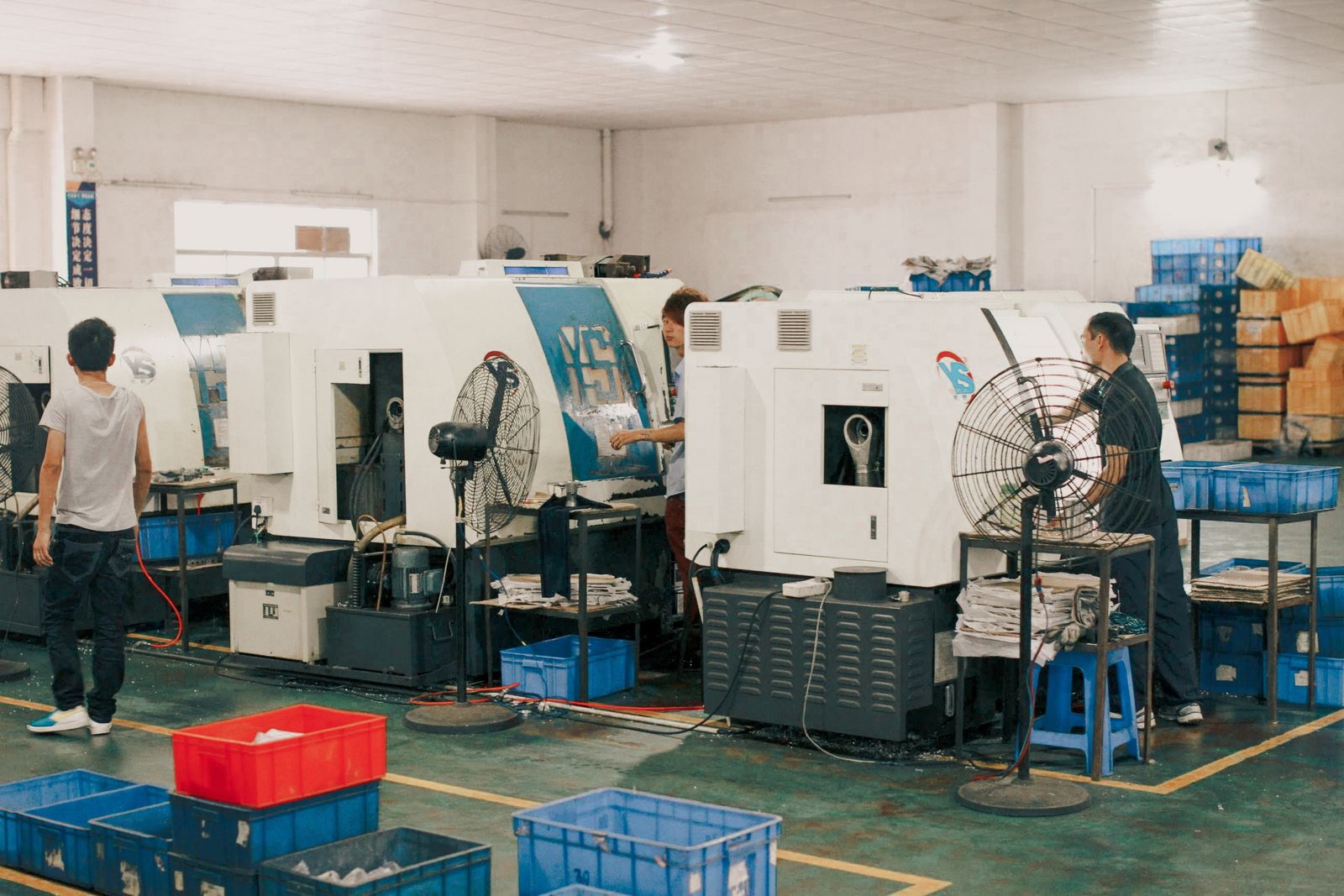 Workers operating production machinery on a manufacturing shop floor
