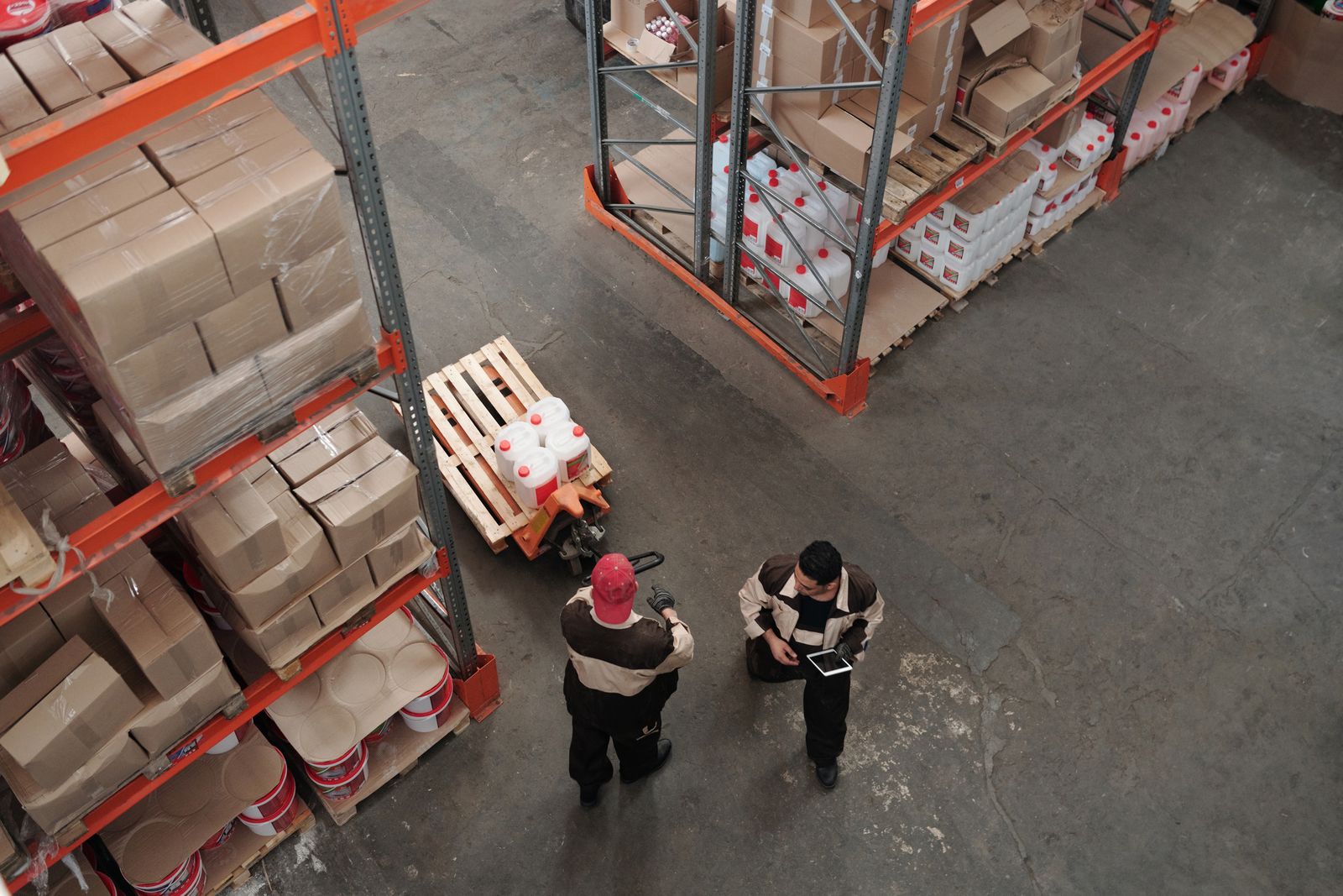 Warehouse team reviewing inventory among pallets and storage racks